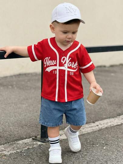 SHEIN Playful Pals 男婴时尚休闲白色棒球夹克短袖上衣搭配浅蓝色牛仔裤套装，白色短袖棒球运动衫饰有蓝色花卉图案和藏蓝色标志，柔软舒适，可爱休闲，适合户外运动，春夏外出、户外玩耍、度假和日常穿着。