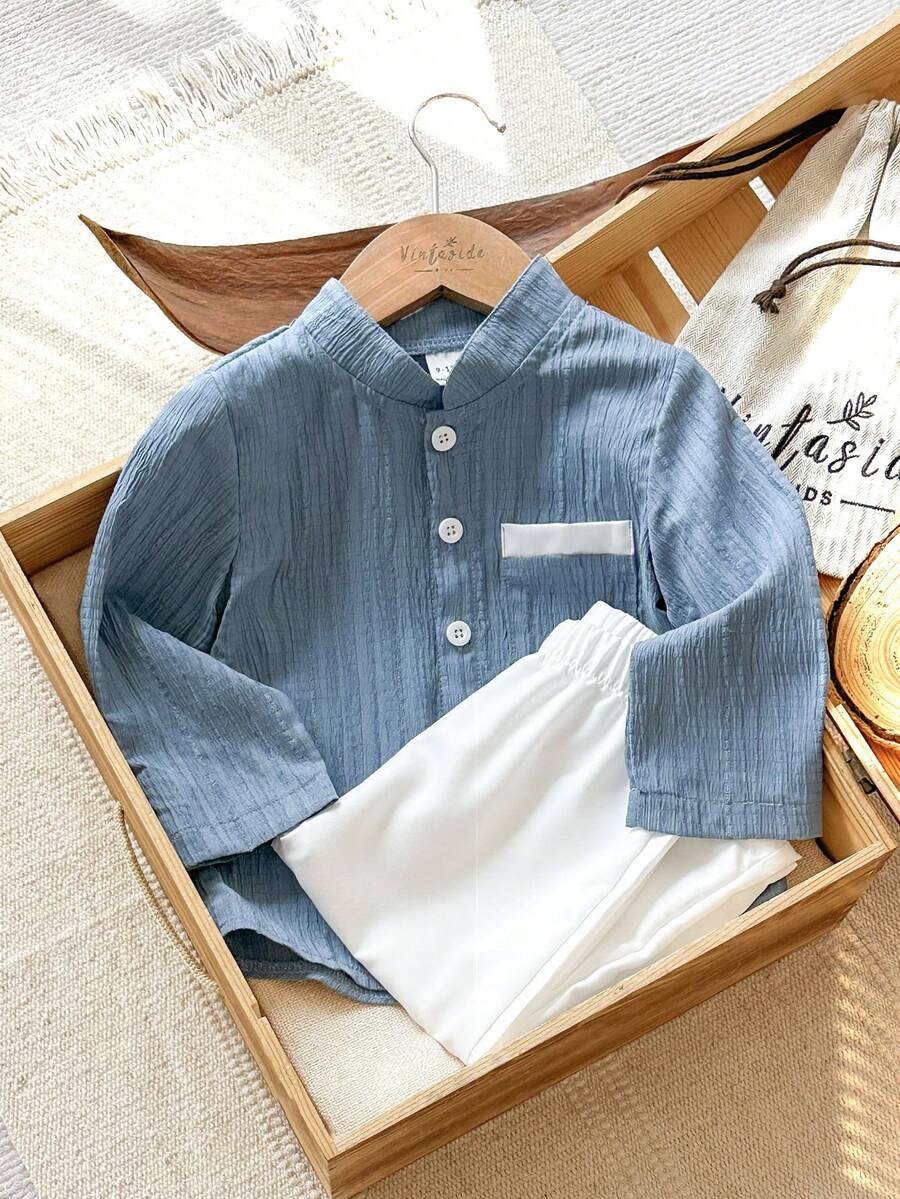 SHEIN Vintaside Kids 这款男童两件套包含一件蓝色提花立领长袖衬衫和一条白色直筒裤，适合春秋季穿着，展现精致优雅的传统中式风格。款式百搭，复古时尚，又不失正式感。宽松的版型、左胸口袋设计和立领设计都散发着浓郁的中国风情。适合日常上学、参加聚会、居家休闲以及正式场合穿着。
