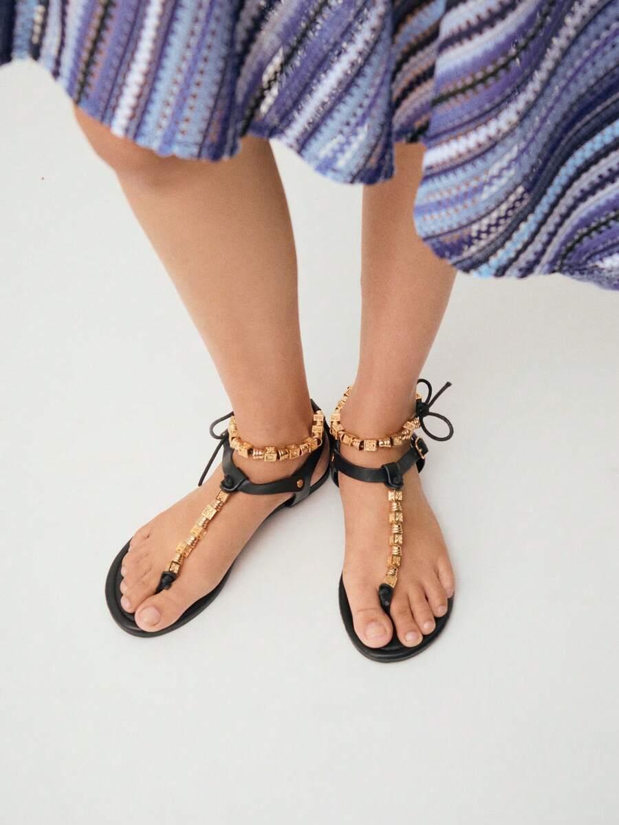 Nöista Embellished Black Thong Sandals. A Sleek Black Sandal Design Featuring A Central T-Strap Adorned With Intricate Gold Geometric Beads-The Perfect Blend Of Bohemian Flair And Refined Elegance. - Black - View 1