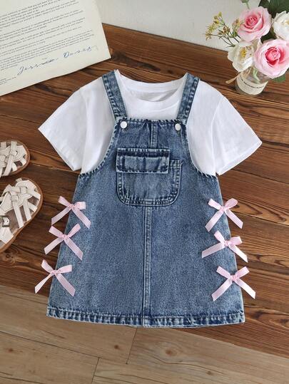 女童甜美可爱牛仔背带裙，春夏款，中蓝色牛仔布，带口袋，粉色蝴蝶结装饰，A字廓形，面料柔软舒适，适合上学和通勤穿着，时尚百搭。