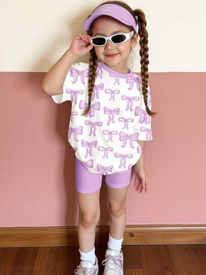 Conjunto de 2 piezas de camiseta de manga corta de cuello redondo holgada con estampado gráfico de lazo y shorts ajustados de ciclista en color morado dulce y elegante, adecuado para uso diario, estilo callejero, salidas, hogar, vacaciones, regreso a clases, primavera y verano