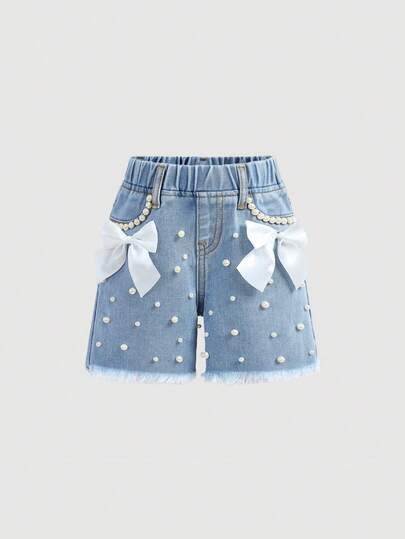 Quần short denim màu xanh nhạt dáng rộng, trang trí nơ ruy băng rộng màu trắng đính ngọc trai cho bé gái.