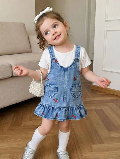 女婴可爱牛仔连衣裙，春夏款，中蓝色牛仔布，红色樱桃刺绣图案，心形贴袋设计，宽松版型，面料柔软舒适，适合派对和日常穿着。