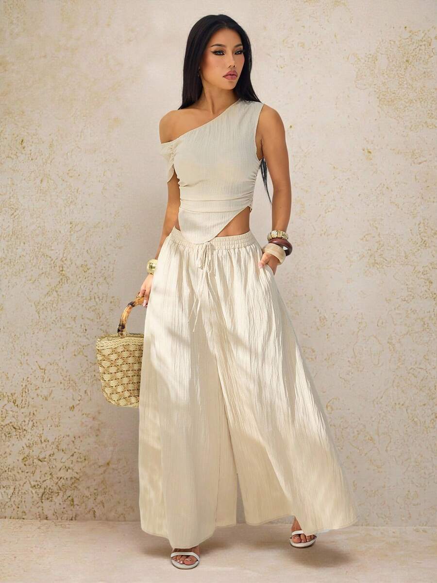 SHEIN PETITE Lễ hội âm nhạc Xuân Hè 2026, Lễ Phục Sinh, Ngày Thánh Patrick, Phong cách miền Tây, Phong cách du mục, Tiệc sinh nhật, Lễ tốt nghiệp, Phong cách đại học, Trang phục sinh viên, Thường ngày, Đa năng, Giải trí, Du lịch tàu biển, Bãi biển, Tắm nắng, Phong cách thịnh hành, Thời trang đường phố, Trang phục dự đám cưới phong cách Boho, Đi làm, Ăn sáng muộn, Trang phục sân bay. Bộ 2 món màu mơ gồm áo crop top lệch vai xếp ly gấu cong và quần ống rộng có túi, chất liệu vải dệt họa tiết. - Màu be - Xem 1