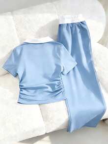 Bộ đồ thể thao thường ngày dành cho nữ tuổi teen, gồm áo polo cổ bẻ với đường chỉ tương phản, thêu ngực, áo tay ngắn cạp xếp ly và quần ống rộng có dây rút. Bộ đồ thể thao màu xanh navy này cân bằng hoàn hảo giữa sự thoải mái và phong cách. Tinh tế nhưng không phô trương, quần ống rộng cạp điều chỉnh được và cổ áo polo tương phản giúp tôn lên đường nét cổ. Một bộ trang phục mùa hè thiết yếu để thư giãn, tập luyện hoặc mặc ngoài trời. - Màu xanh lam - Xem 2