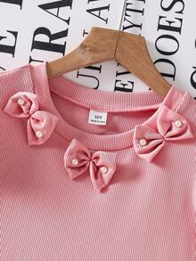 Cet ensemble se compose de deux pièces pour filles : un Top court et ajusté avec un col rond, des manches volantées et une décoration de nœud au col, le nœud étant orné de perles ; ainsi que des pantalons ajustés et évasés avec des décorations de perles aux ourlets. Idéal pour le port décontracté au quotidien en été. - Rose bonbon - Voir 4