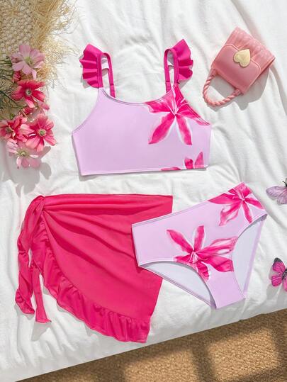 SHEIN Bộ bikini 3 mảnh dành cho bé gái tuổi teen, phong cách nghỉ mát ngọt ngào, nền màu hồng nhạt với họa tiết hoa màu hồng cánh sen khắp thân áo, áo hai dây xếp nếp, quần cạp cao in hoa cùng màu, chân váy lưới màu hồng, chất liệu vải dệt kim, thời trang, giản dị, thanh lịch, thích hợp cho bơi lội, kỳ nghỉ hè, bãi biển, hồ bơi, tiệc tùng, kỳ nghỉ thư giãn.