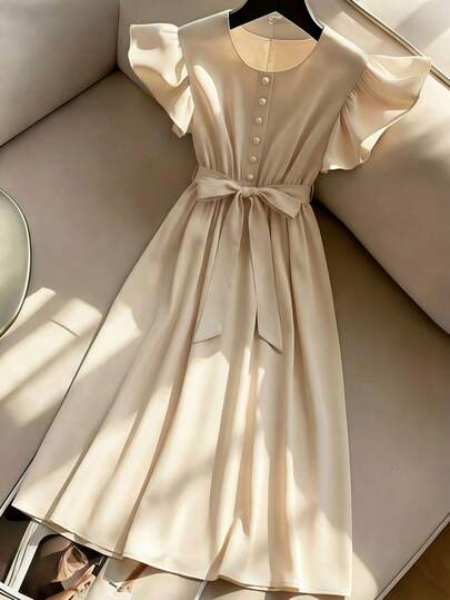 Franclia 这款连衣裙采用修身剪裁，圆领设计搭配飘逸的荷叶袖，一排珍珠纽扣和腰间蝴蝶结更添甜美气息。面料挺括顺滑，做工精细。整体设计简约优雅。乳白色，适合正式和高雅场合穿着。