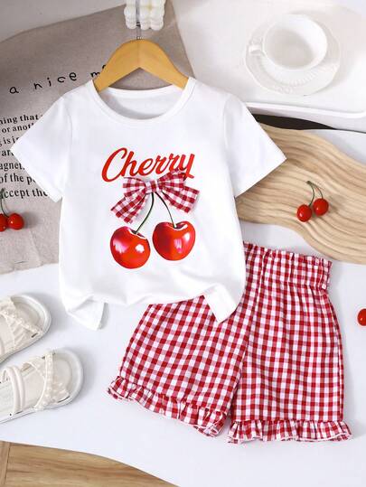 Bộ 2 món cho bé gái: Áo thun in hình quả anh đào, kẻ caro, trang trí nơ và quần short kẻ caro viền bèo.