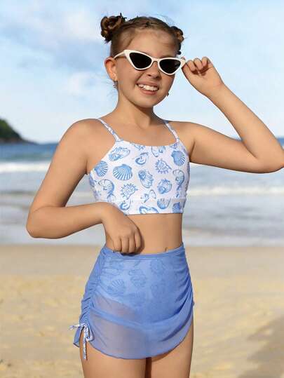 SHEIN Bộ đồ bơi 3 mảnh cho bé gái: Áo và quần tankini in họa tiết hoa xanh ngẫu nhiên, kèm khăn sarong màu xanh trơn. Phong cách nghỉ mát biển đáng yêu, thích hợp cho bơi lội và các hoạt động trên bãi biển mùa hè.