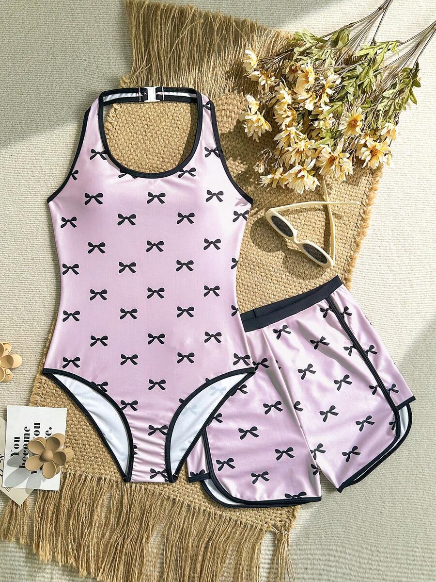 SHEIN Bộ đồ bơi liền thân cổ yếm in nơ cho bé gái tuổi teen, màu đen và hồng, in nơ + quần short cùng màu. Phong cách mùa hè mới, thân thiện với da và nhanh khô. Thiết kế lưng chữ Y, che phủ toàn bộ hông để tránh hở hang. Trang phục đi biển/hồ bơi sành điệu. Món đồ không thể thiếu cho phong cách ngọt ngào và nữ tính. Đồ bơi cho bé gái tuổi teen, đồ bơi cho tuổi teen, đồ bơi cho bé gái, lựa chọn mùa xuân hè, trang phục mùa hè cho nữ, bộ đồ bơi cho tuổi teen, đồ bơi dễ thương cho tuổi teen, đồ bơi che phủ toàn thân cho tuổi teen, đồ bơi liền thân. - Hồng - Xem 1