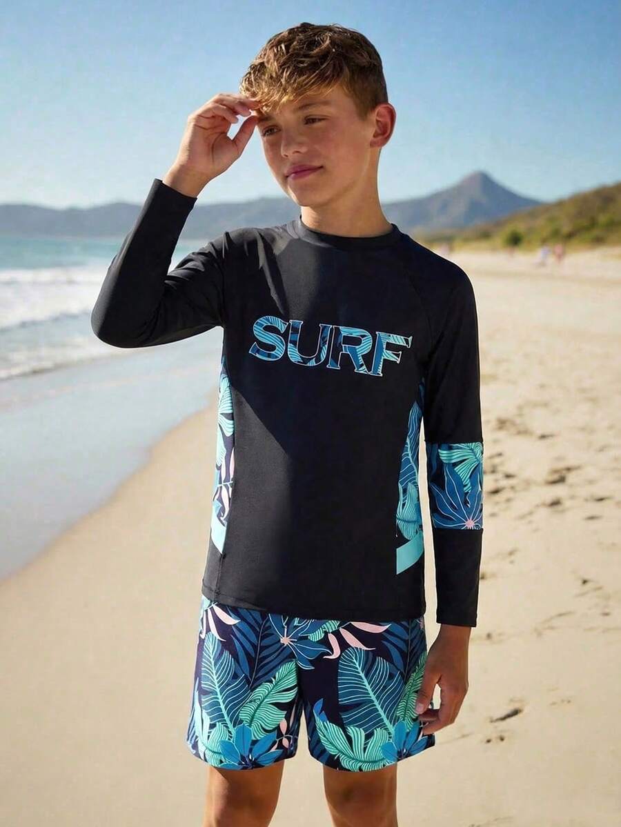 SHEIN 男童泳装,酷炫冲浪风,纯黑色,正面饰有渐变蓝色“SURF”字母印花,插肩袖,侧边热带花卉印花,两件套,针织面料,时尚休闲,适合游泳、夏季度假、海滩、泳池派对等场合。 - 黑色 - 查看 1