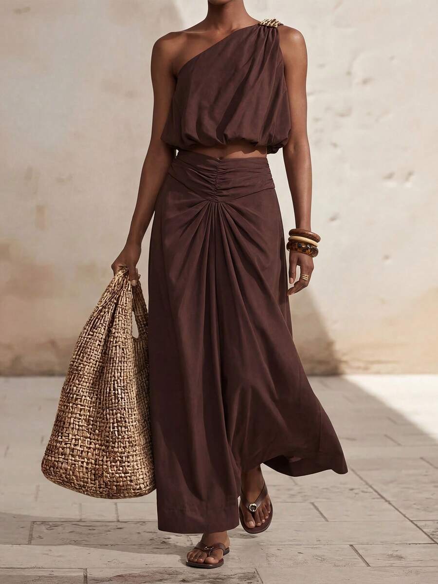 Zivah Bộ đồ đi nghỉ mát năm 2026: Áo trễ vai độc đáo kết hợp với chân váy midi màu nâu đậm thanh lịch, xếp ly eo.
