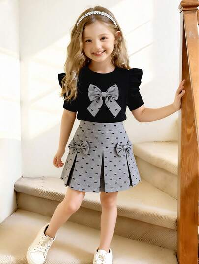 两件套女童黑色提花针织圆领喇叭袖T恤，配灰色蝴蝶结装饰和灰色梭织松紧腰半身裙，适合春夏日常、户外、旅行、派对等场合。