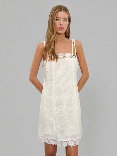Nöista Đầm ngắn màu trắng thêu hoa với phần thân trên ôm sát và chân váy xòe nhẹ. Thiết kế cổ áo thẳng, dây đeo vai buộc điều chỉnh được và viền ren lượn sóng. Thích hợp cho các bữa tiệc mùa hè, sự kiện cưới, kỳ nghỉ, sự kiện trang trọng, mùa xuân, lễ hội âm nhạc, đi biển.