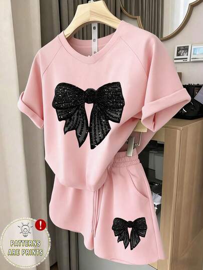 一套少女休闲舒适时尚简约创意蝴蝶结装饰印花短袖T恤和短裤套装，适合春夏日常穿着，插肩袖设计。