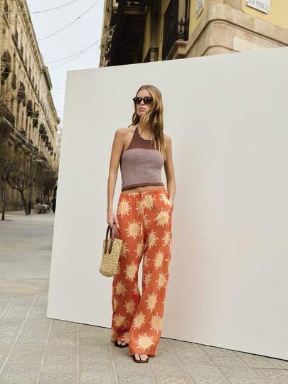 Nöista Quần ống rộng dáng suông với họa tiết hoa hướng dương tông màu cam, thiết kế ống đứng rộng. Thoải mái và đa năng, hoàn hảo cho mùa hè, lý tưởng cho trang phục thường ngày, đi biển hoặc du lịch.