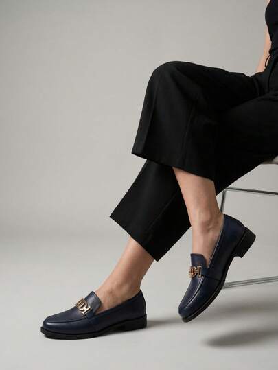 Mocasines clásicos con diseño tipo slip-on, estructura elegante de punta redondeada, tacón cuadrado; acabado brillante en materiales sintéticos, detalle decorativo de herraje metálico en tono dorado sobre el antifaz, costuras finas y suela de goma dentada con propiedades antideslizantes, interior forrado con plantilla suave para máximo confort durante el día, perfectos para atuendos formales y casuales, disponibles en diferentes colores distintivos y sofisticados, modelo amplio de forro suave