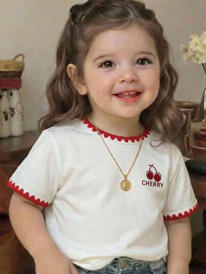 SHEIN Camiseta de manga corta con cuello redondo, gráfico de letras de cereza, ribete floral para bebé/niña de 6M-3T, ropa de bebé/niña pequeña, sudadera de niña, camiseta de manga corta de niña, camiseta blanca versátil de manga corta de niña, artesanía de ribete en el cuello y el bajo de la manga, elemento de cereza, elemento de fruta, elemento en inglés, adecuado para primavera/verano, verano