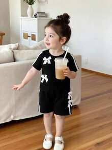 SHEIN Baby Girls' Chic 2-Piece Black Outfit Set, Short Sleeve Crew Neck Top With White Bow Accents & Side Stripe Details, Matching Elastic Waist Shorts With Bows, Ultra-Soft Lightweight Breathable Fabric, Sweet Sporty Casual Style For Everyday Wear, Playdates & Outdoor Activitie - Black - View 9