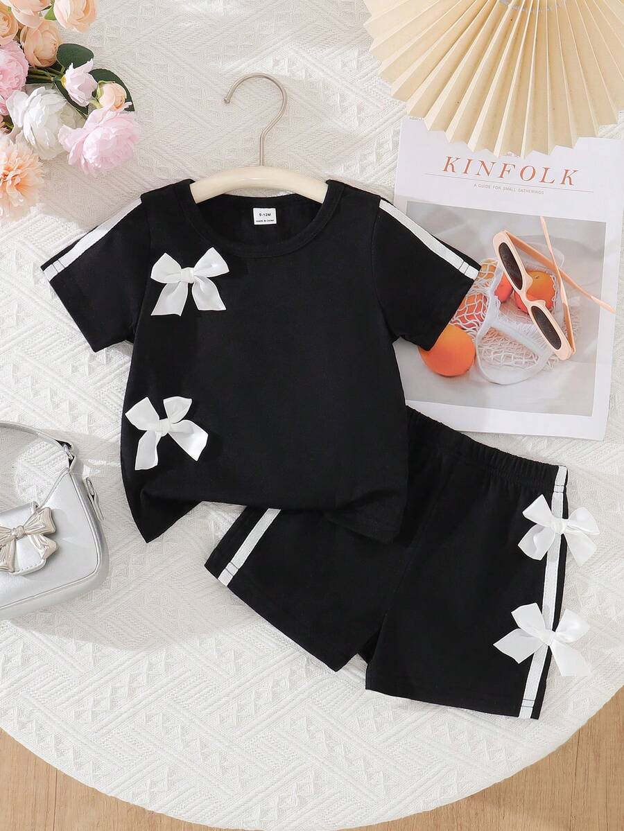SHEIN Baby Girls' Chic 2-Piece Black Outfit Set, Short Sleeve Crew Neck Top With White Bow Accents & Side Stripe Details, Matching Elastic Waist Shorts With Bows, Ultra-Soft Lightweight Breathable Fabric, Sweet Sporty Casual Style For Everyday Wear, Playdates & Outdoor Activitie - Black - View 1