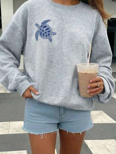 SHEIN EZwear Sudadera holgada de cuello redondo de manga larga en gris claro, con gráfico de tortuga marina, estilo casual retro, adecuada para la playa, festivales de música, vacaciones, que muestra el ambiente de Miami. Es la opción ideal para la temporada de regreso a clases y el vestuario de otoño/invierno para mujeres. Esta sudadera con hombros descubiertos/sudadera con gráfico de tortuga marina/sudadera gris/top de verano es la elección perfecta para la temporada de regreso a clases y otoño/invierno.