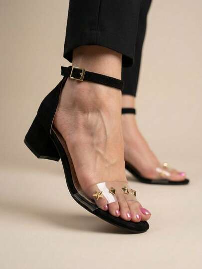 Elegantes sandalias negras de tacón para mujer, tacón de 2 cm para mayor comodidad, con tachuelas en forma de estrella y hebilla ajustable. Sandalias de tacón de bloque para mujer con tira transparente con tachuelas en la puntera y cómoda hebilla en el tobillo.