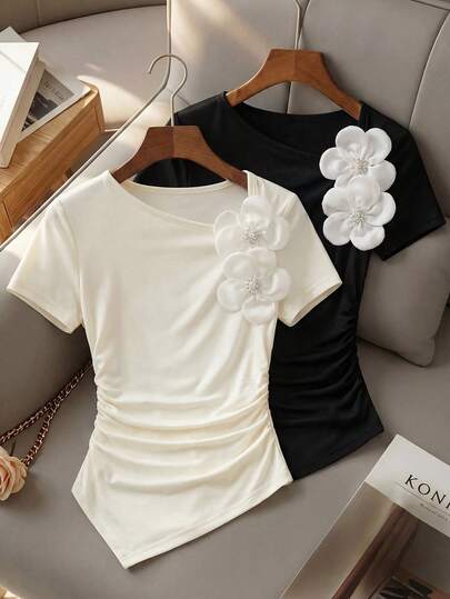 少女两件套不对称下摆褶皱T恤——时尚短袖上衣，肩部饰有精美细节。这套两件装专为追求时尚的女孩设计，包含一件经典的象牙色和一件时尚的黑色短袖T恤。每件单品都采用独特的不对称下摆设计，侧边褶皱勾勒出优美身形，肩部饰有精致的装饰细节，巧妙融合了舒适感与现代时尚。适合日常穿着、上学或休闲外出。
