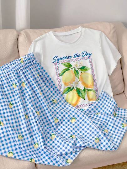 SHEIN 这款少女T恤套装以清新柠檬为主题，充满夏日气息。上衣是一件简约的白色短袖T恤，正面印有柠檬枝和花朵图案，搭配“Squeeze The Day Lemon Zest”（感受每一天的柠檬活力）英文标语，传递积极的生活态度。下装是一条蓝白格纹阔腿裤，饰有小巧的柠檬图案，与上衣元素相呼应。整体风格清新舒适，适合居家休闲、户外运动或上学穿着，营造轻松愉悦的日常氛围。