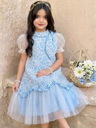 SHEIN 这款浅蓝色女童花卉提花网纱连衣裙，配有可拆卸领口荷叶边、泡泡袖和荷叶边下摆，面料柔软，适合多个季节穿着。清新花卉图案搭配梦幻网纱设计，休闲/派对皆宜。宽松版型，易于搭配和打理，打造甜美飘逸的少女造型。