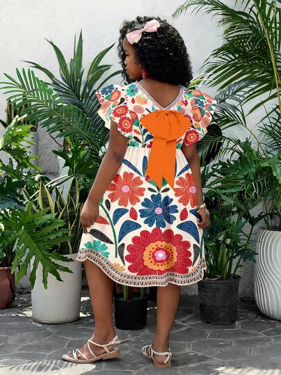 Đầm cho bé gái tuổi teen với họa tiết hoa rực rỡ phủ khắp thân đầm, điểm nhấn là chiếc nơ màu cam đáng yêu ở phía sau, tay áo bồng bềnh, cổ chữ V với tua rua nhiều màu sắc. Thích hợp cho những buổi đi chơi hàng ngày và các dịp lễ hội, kết hợp giữa sự ngọt ngào và cá tính.