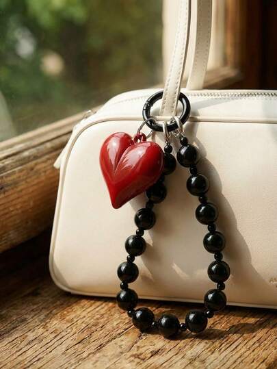 Joivida 这款红色心形黑色串珠手机手链，单环设计，配有光泽闪亮的心形吊坠和抛光珠子，适合日常佩戴、旅行和包包装饰。它是馈赠亲朋好友的绝佳节日礼物，也是情人节送给情侣和时尚达人的理想之选。它兼具时尚感和情感元素，是完美之选。