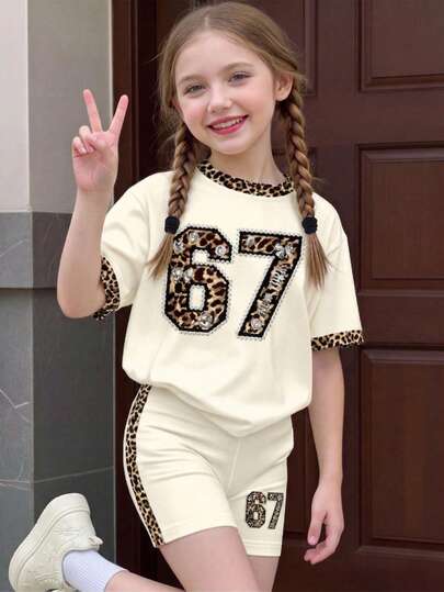 Bộ đồ cho bé gái tuổi teen, phong cách thường ngày tối giản, màu trắng kem in họa tiết da báo cổ điển, gồm áo thun ngắn tay và quần short, với nền màu trắng kem in họa tiết da báo cổ điển và nơ đính đá, họa tiết "67" vui nhộn, kết hợp với quần short họa tiết da báo, thích hợp cho các buổi đi chơi, thể thao, mua sắm và các dịp khác.