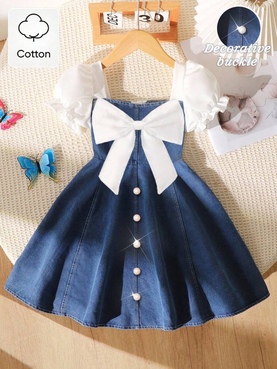 Elladie kids 少女春夏休闲时尚连衣裙，正面饰有白色蝴蝶结，前摆饰有白色金属珍珠纽扣，白色纯色梭织面料，短款泡泡袖拼接蓝色牛仔腰身，适合春夏返校季穿着，甜美可爱，尽显淑女风范，适合日常上学、外出、度假、拍照等春夏穿着。夏季服装，柔软舒适，充满海岛风情，适合海滩周末度假。少女服装，可爱连衣裙。 - 中等水洗藍 - 查看 1