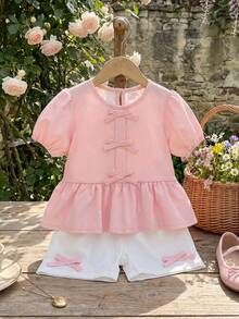 Souflis Souflis Nouveau ensemble mode été français pour bébé fille, avec Top à col rond et manches courtes avec imprimé nœud délicat, décoré d'un ourlet à volants, assorti à un short blanc avec accent nœud. Tenue adorable et à la mode, convient pour l'école, les sorties et les jeux. - Rose bonbon - Voir 2