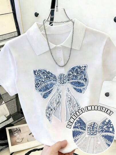 Resyla Áo thun nữ tay ngắn cổ tròn, dáng casual, in hình nơ và đính ngọc trai.