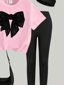 SHEIN Sparklyn Bộ đồ thể thao mùa xuân hè cho bé gái, phong cách thường ngày sáng tạo, cá tính, tối giản, điểm nhấn là nơ đen bóng, in họa tiết đồ họa, gồm áo thun và quần legging, thoải mái để mặc hàng ngày. - Nhiều màu - Xem 5