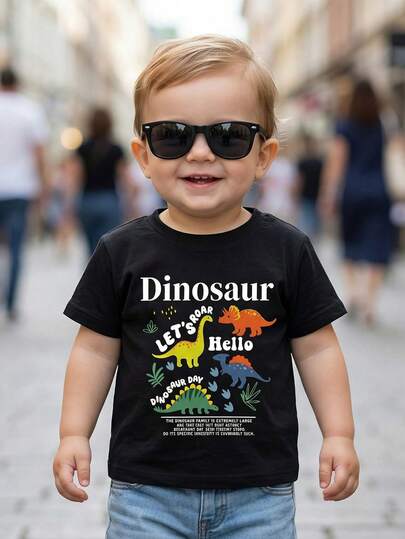 SHEIN Playful Pals Áo thun ngắn tay cổ tròn màu đen in hình khủng long và chữ cái cho bé trai, quần áo trẻ em, áo cho bé trai sơ sinh và trẻ nhỏ, áo chui đầu cho bé trai sơ sinh và trẻ nhỏ, áo thun ngắn tay cho bé sơ sinh và trẻ nhỏ, thích hợp cho lễ Phục sinh, tiệc tùng, mặc thường ngày, kiểu dáng ngọt ngào và dễ thương, thiết kế khủng long và chữ cái, thích hợp cho mùa xuân/hè, phù hợp cho bé từ 6 tháng đến 3 tuổi.