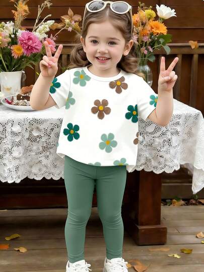 Bộ đồ cho bé gái gồm áo thun ngắn tay in hoa và quần legging màu trơn, trang phục dễ thương cho những chuyến đi chơi mùa hè.