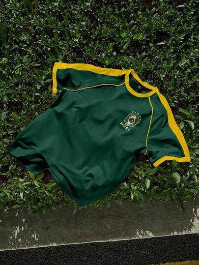 Manfinity EMRG Áo thun nam tay raglan rộng màu vàng và xanh lá cây, thiết kế kiểu áo bóng đá màu vàng với viền xanh lá cây và vàng ở tay áo và cổ áo, huy hiệu màu xanh lá cây ở ngực trái, và chữ "BRASIL" lớn màu xanh lá cây cùng số "7" màu vàng ở phía sau. Thích hợp mặc hàng ngày, kiểu dáng thể thao năng động, là món quà tuyệt vời cho bạn trai, chồng hoặc người yêu.
