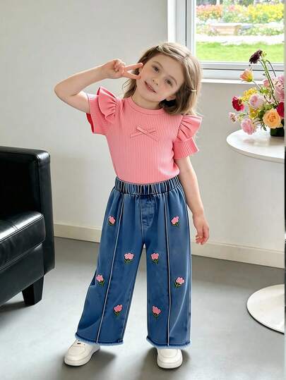 Bộ đồ bé gái màu hồng và cam gồm áo thun tay phồng ngắn có nơ và quần jean ống đứng thêu hoa, trang phục mùa hè ngọt ngào và dễ thương.