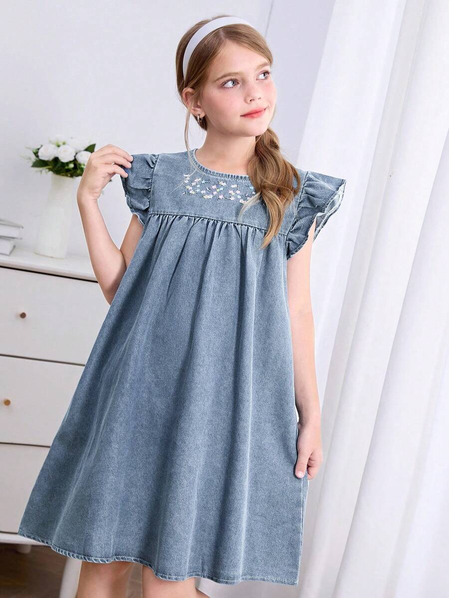 SHEIN 2026新款女童牛仔连衣裙，夏季时尚休闲风。浅牛仔蓝，荷叶边袖口饰以花卉刺绣，宽松A字廓形。采用柔软轻盈的棉质牛仔面料，是女孩们的时尚必备单品。简约休闲设计，适合夏季穿着，日常出行、派对、音乐节、度假等各种场合。