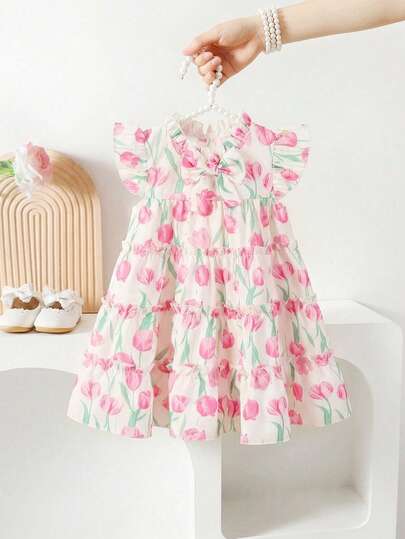 Souflis Souflis Baby Girl Elegant Luxurious Cute Cake Skirt Dress, Featuring Multi-Layer Cake Skirt Design, The Dress Body Is Composed Of Layered Ruffled Tiers That Naturally Drape To Form A Fluffy A-Line Silhouette, Visually Light And Dynamic With Abundant Layers. Round Neckline With A Matching Fabric Bow Accent At The Center, Adding Sweetness; Shoulder Features Small Flutter/Ruffle Sleeves