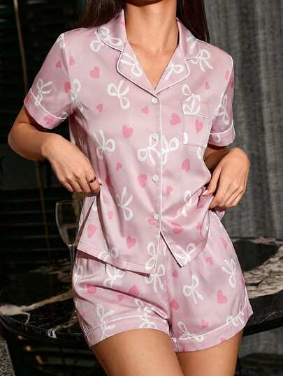 女童白色蝴蝶结爱心印花粉色底经典领开衫，短袖设计，白色滚边，左胸口袋，纽扣前襟，穿着方便 - 配套短裤，松紧腰带，白色滚边，宽松版型，适合夏季居家休闲、睡衣穿着、空调房穿着，冰丝面料，阻燃睡衣套装