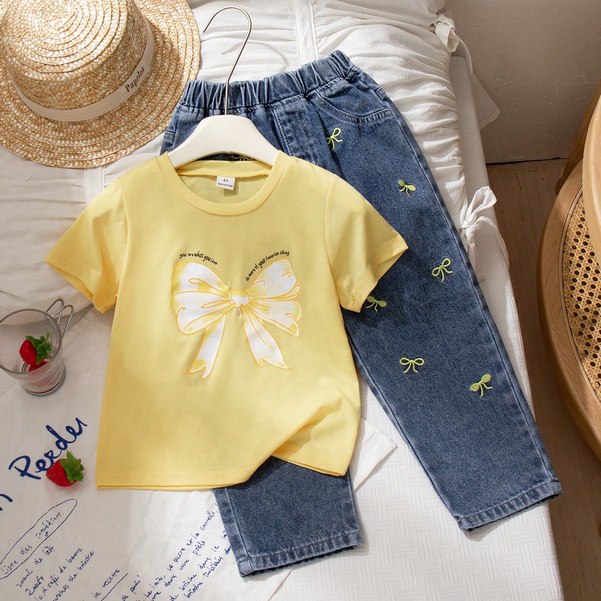 Conjunto casual y cómodo para niñas pequeñas con camiseta de manga corta de cuello redondo con estampado de moño y pantalones largos de mezclilla
