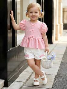 Souflis Souflis Nouveau ensemble mode été français pour bébé fille, avec Top à col rond et manches courtes avec imprimé nœud délicat, décoré d'un ourlet à volants, assorti à un short blanc avec accent nœud. Tenue adorable et à la mode, convient pour l'école, les sorties et les jeux. - Rose bonbon - Voir 4