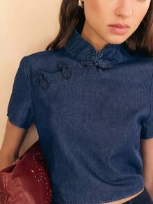 2026 Blusa de manga corta con cuello mao de denim, con detalles de botón de nudo tradicional y corte entallado.Minimalista pero distintiva, la blusa moderna inspirada en el chino es perfecta para un estilo casual, básicos elevados y looks primaverales con un toque único.Ligera, versátil y fácil de combinar. - Azul lavado medio - Ver 3