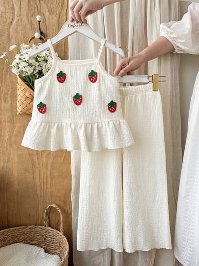 Vintaside Kids 少女春夏米色休闲时尚度假乡村风宽松短款抹胸上衣搭配直筒裤两件套。饰有草莓印花。采用质感绉纱面料制成。正面饰有立体草莓印花。下摆采用荷叶边设计。宽松版型适合日常外出、家庭野餐、休闲放松、运动穿着、生日派对、春季花园派对等场合。