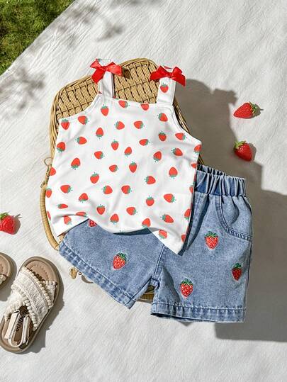 SHEIN Vintaside Kids Bộ đồ hai mảnh cho bé gái gồm áo yếm kiểu dáng mùa hè mới và quần short denim, mang phong cách thời trang, tươi mới, mộc mạc và dễ thương. Được làm từ chất liệu vải dệt kim và denim. Dây đeo vai mỏng được trang trí bằng nơ đỏ và in họa tiết dâu tây. Gấu quần được thêu hình dâu tây. Kiểu dáng rộng rãi, phù hợp cho các hoạt động hàng ngày. Thích hợp làm quà tặng sinh nhật một tuổi, quà cưới, quà du lịch.