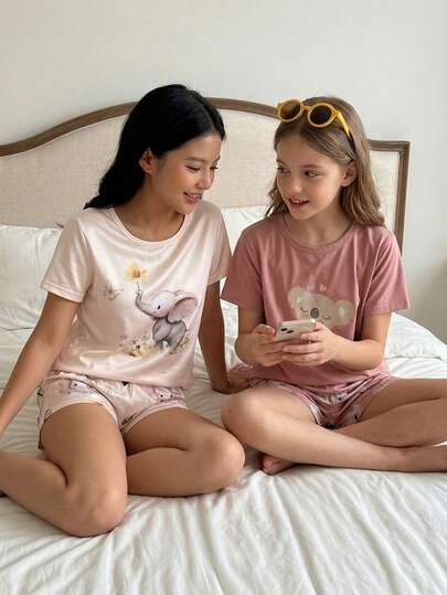 Bộ đồ ngủ 2 món cho bé gái, gồm quần short và áo tay ngắn in hình gấu, màu hồng nhạt.